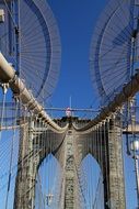 view from below of Brooklyn Bridge in the blue sky