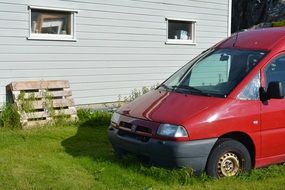 red car on green grass near the house