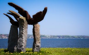 stone sculpture on green grass near the water