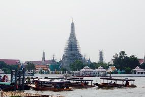 boats at pier in view of Buddhist temple complex, Thailand, bangkok