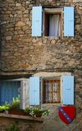 blue Open Shutters on facade of old stone building, France