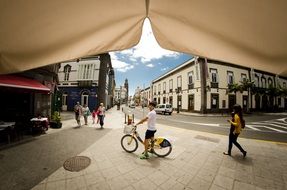 cyclist and people on the street view from under the umbrella