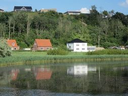 houses are reflected in the water on the picturesque shore