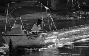 man in speedboat in black and white