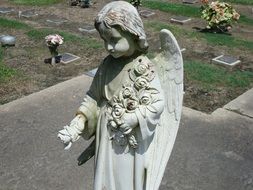 angel with roses as a sculpture in a cemetery