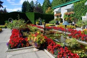 colorful flower beds and potted flowers in front of house