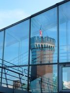 mirror image of a tower in a glass facade