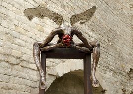 winged man with open brains, modern sculpture at old stone wall, Spain, Barcelona
