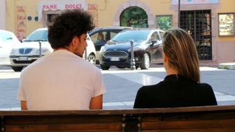 couple in love sits on a bench and cars