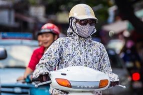 girl in a helmet and a mask on a scooter in Hanoi