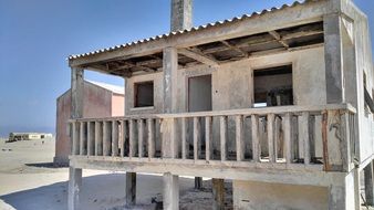 stone building with a balcony on the sandy beach at blue sky background