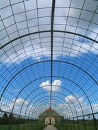 glass arched passage under blue sky with fluffy clouds