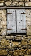 old house with stone built wall and wooden window in Oriklini, Cyprus