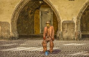 bronze statue of a man among a historic street with the arches