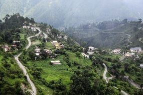 road on a green hill near houses