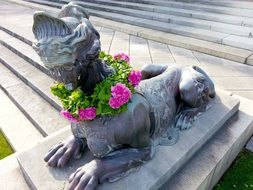 stone sphinx statue with flowers in a park