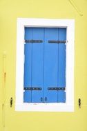 blue window shutters on the yellow wall