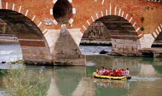 inflatable boat with people near the stone bridge