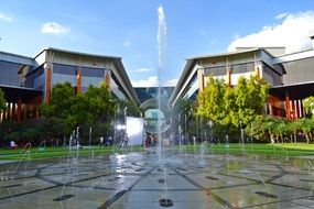 modern fountain in the square among the buildings and plants