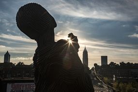 metal sculpture against the backdrop of a city sunset