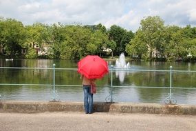 woman with a red umbrella by the pond in the park, dusseldorf