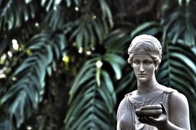 monument of a woman on the background of leaves