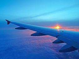 the sun is in the sunset behind the wing of the plane