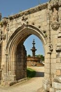 view of fountain through gothic stone arch, france, brittany