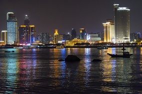 boats in the harbor against the backdrop of skyscrapers at night