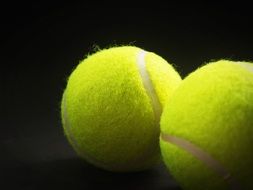 two yellow tennis balls on black background