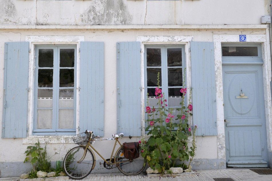 a bicycle stands near a house with blue walls