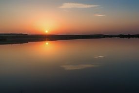 sunset on the horizon of quiet water in the lake