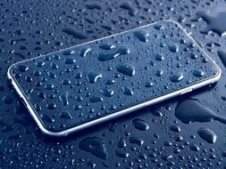 Iphone and black surface in water drops