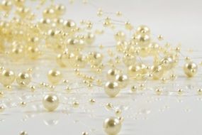 golden beads on a thin thread on a white surface