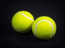 yellow tennis balls with white stripes on a dark background