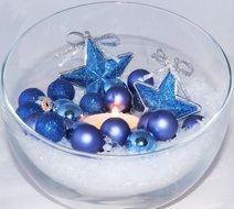 Christmas decorations and lit candle in glass bowl