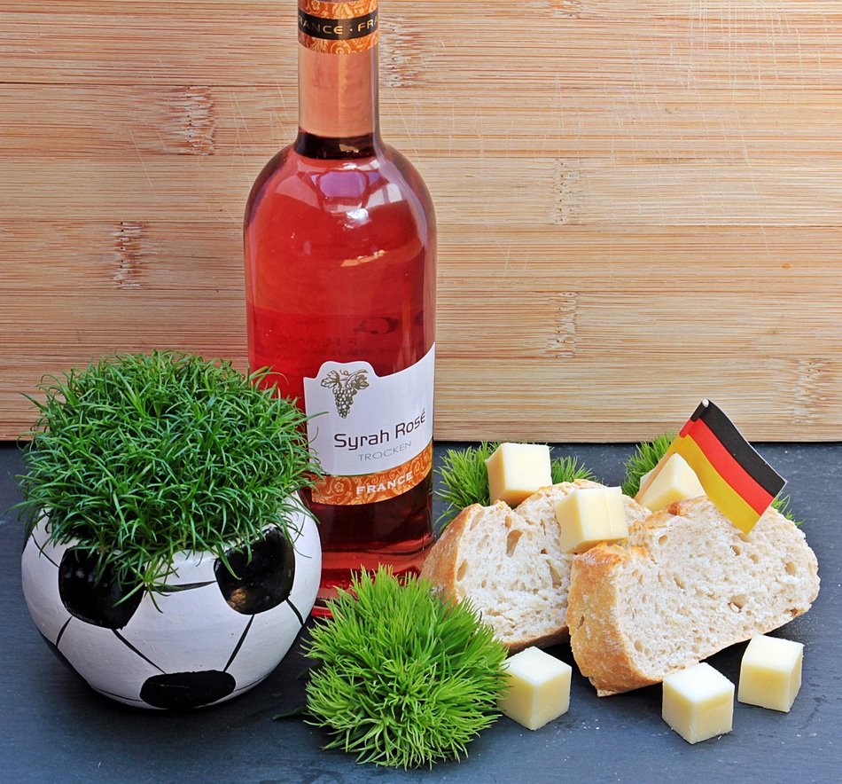 a bottle of wine and cheese near the soccer ball