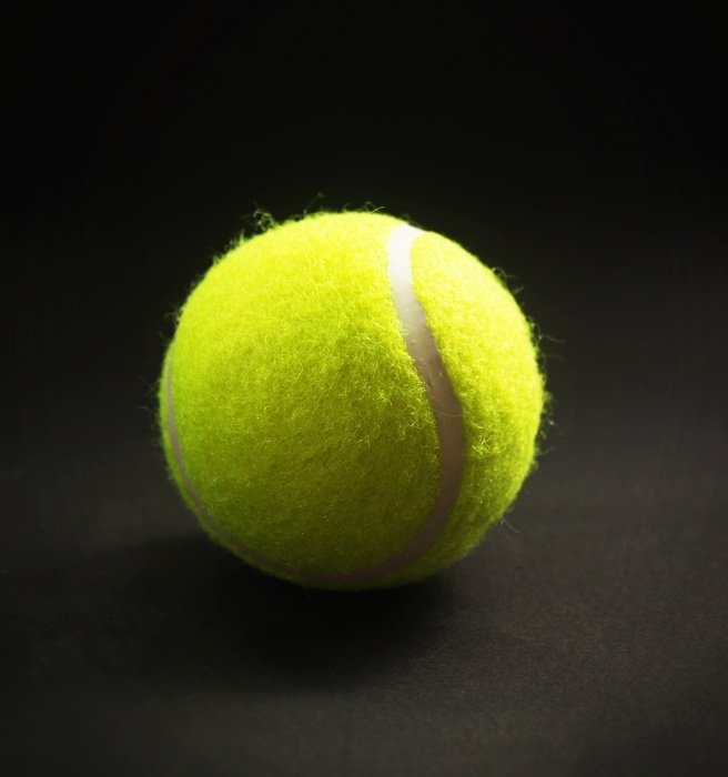 yellow tennis ball on the black background