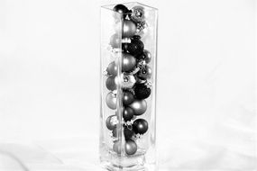 Christmas baubles in glass vase in black and white