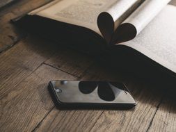 smartphone and book with heart made of pages