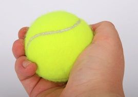 yellow tennis ball in human hand