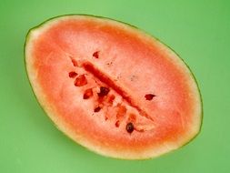 piece of watermelon with seeds on a green background