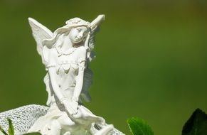fairy statue with wings on green blurred background