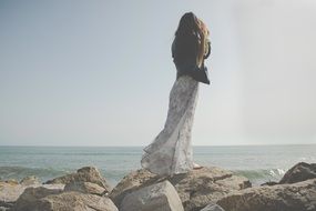 young woman on the stones on the coast