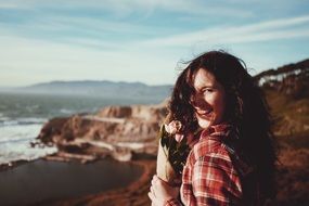 laughing girl with a bouquet on the coast