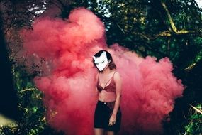 Woman in a mask in a pink smoke