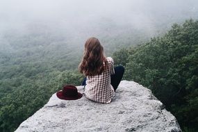 girl in checkered shirt on top of the cliff with a lot of plants around