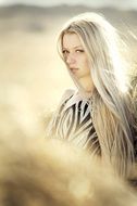 blonde with long hair on a background of a rural field
