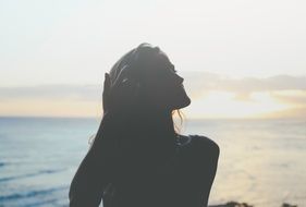 Woman is posing on the beach under sunset