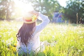 pretty woman in the hat sitting in the meadow